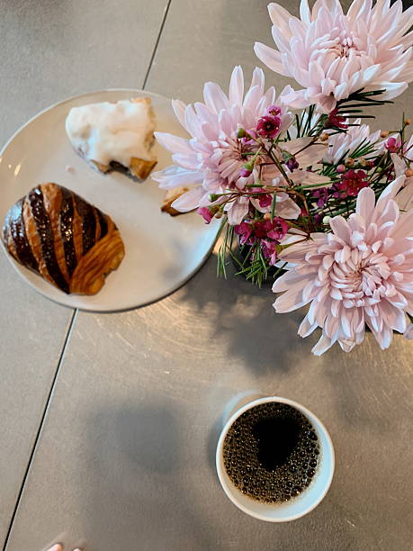 A Directly Above View of Hot Black Coffee with Bubbles, a Raspberry Chocolate Croissant, a Scone, and Pink Flowers in a Local Coffee Shop in Sunny West Palm Beach, Florida, in May of 2025