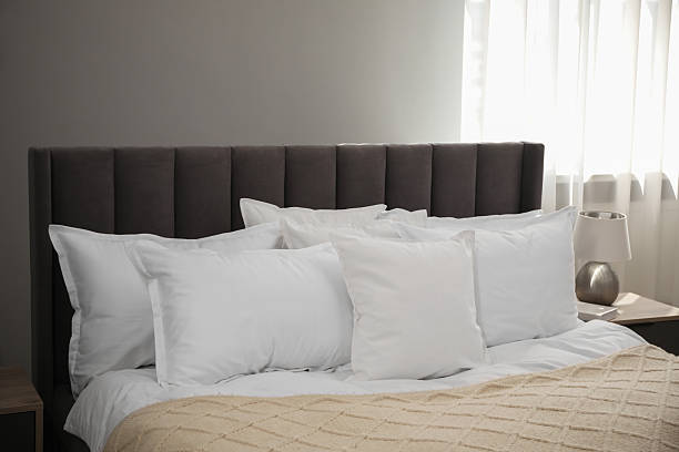istock Many soft white pillows and knitted blanket on bed indoors 2226851949