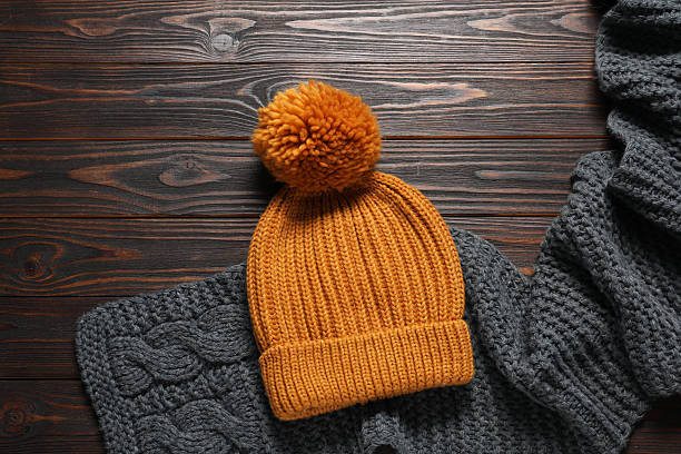 istock Knitted scarf and hat on wooden table, top view. Space for text 2226851978