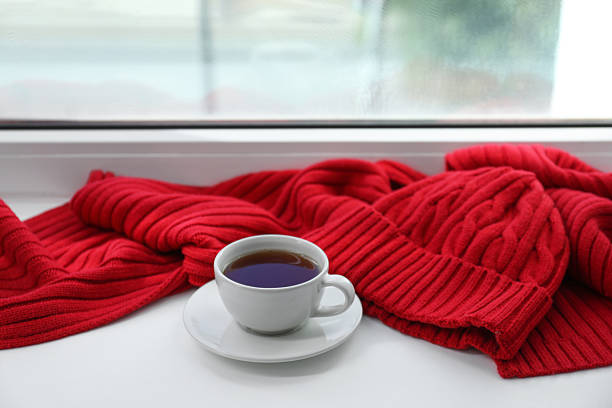 Red knitted scarf, hat, tea on windowsill