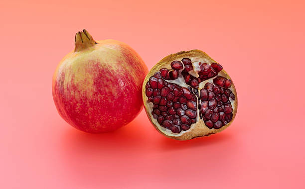 istock One and a half pomegranates on red background 2226852236