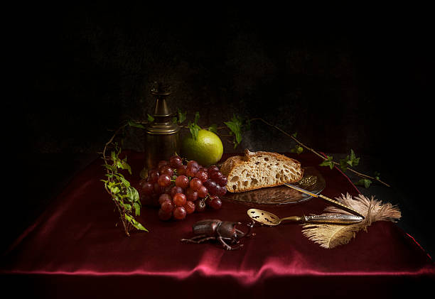 Baroque still life with red grapes, rustic bread and lemon on a maroon satin fabric, europe