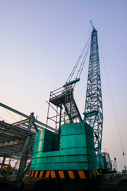 Towering ambition: A construction crane reaches skyward against the pale blue backdrop