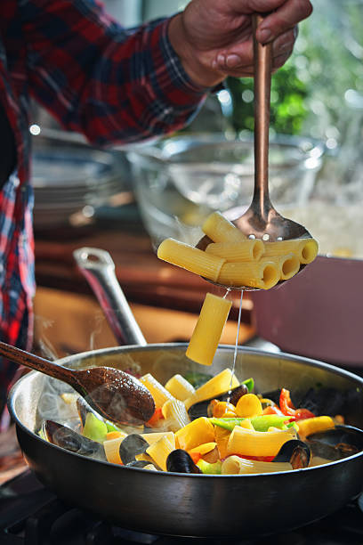 Preparing Rigatoni Pasta with Blue Mussels and Mixed Peppers in Domestic Kitchen
