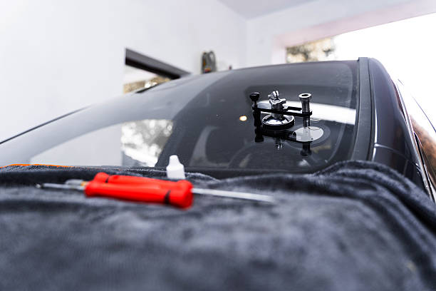 istock Resin repair on windshield using injector application to restore structural clarity. Windshield crack repair using resin injection. Technician using windshield injector tool to fix bullseye crack. 2226864809