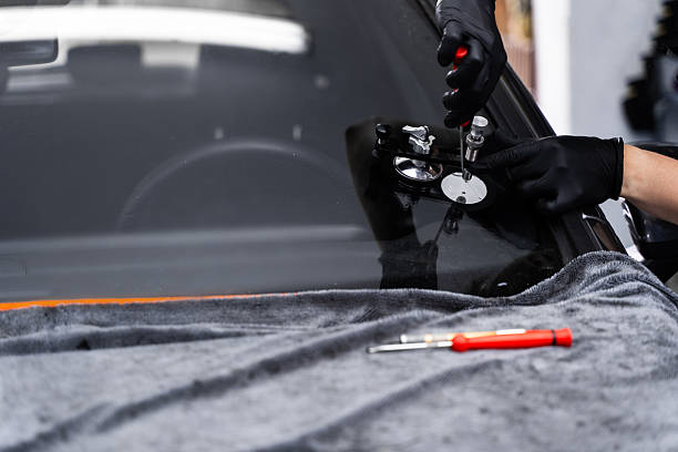 istock Resin repair on windshield using injector application to restore structural clarity. Windshield crack repair using resin injection. Technician using windshield injector tool to fix bullseye crack. 2226864842