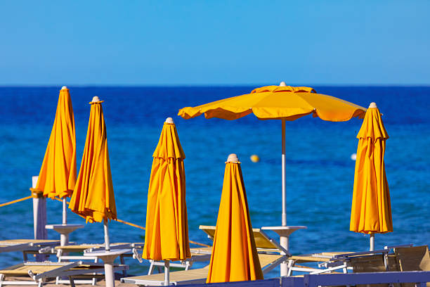 Bright yellow beach umbrellas stand over the tranquil blue sea. Beach umbrellas stand guard over the tranquil blue sea