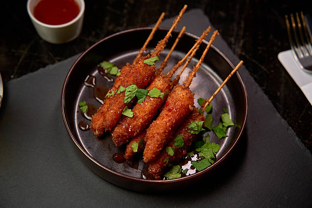 istock Savory Skewered Delights: Crispy Fried Appetizers Garnished with Fresh Herbs and Accompanied by a Tangy Dipping Sauce for a Flavorful Experience 2226871604
