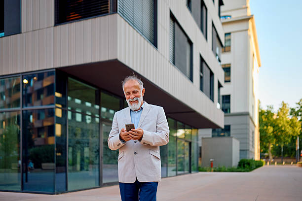 istock Senior businessman using smartphone while walking near modern office building 2226872222