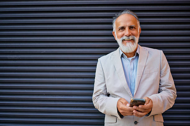 istock Smiling businessman using smartphone in front of gray background 2226872268