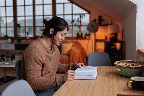 istock Thoughtful Japanese Man Reading at Dining Table 2226875053