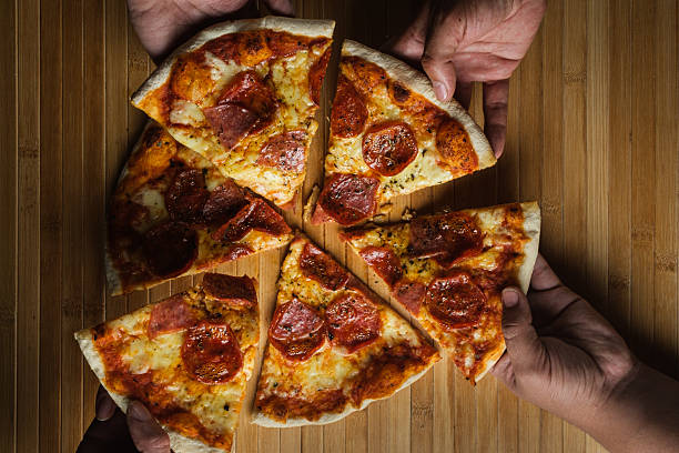 istock Friends sharing delicious pepperoni pizza on wooden table 2226875138