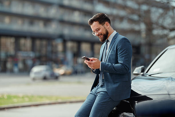 istock Businessman Checking Smartphone Beside CarDescription: 2226877249