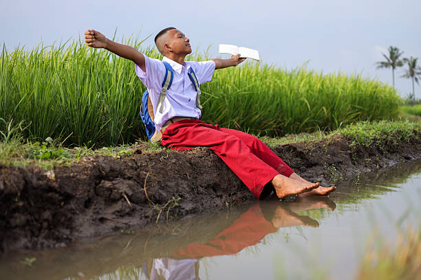 Indonesian Student In Uniform Relaxing And Enjoying Book In The Natural Outdoors