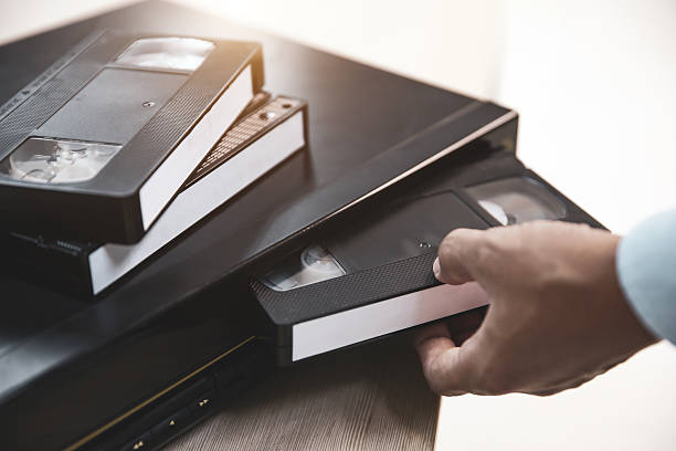 istock Close-up hand put or insert video cassette tape VHS old retro style on video record playback concept of vintage electric and electronic appliances multimedia player device old fashioned. 2226885341