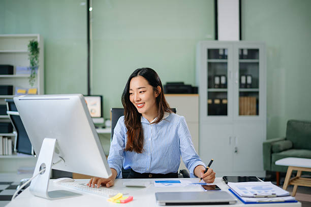 istock Asian businesswoman analyzes data charts on her desktop in a modern office, showcasing professional productivity, digital innovation, and real people 2226893605