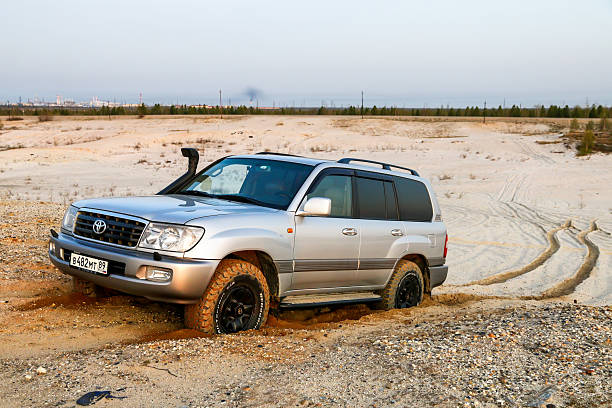 Novyy Urengoy, Russia - June 11, 2025: Grey offroad car Toyota Land Cruiser 100 climbing the sand hill.