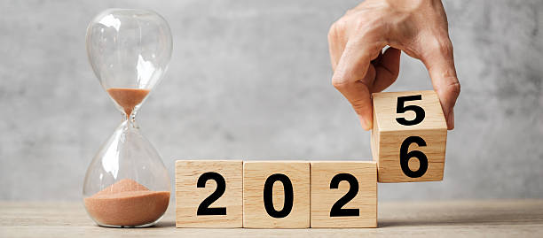 istock hand flipping block 2025 to 2026 text with hourglass on table. Resolution, time, plan, goal, motivation, reboot, countdown  and New Year holiday concepts 2226898096