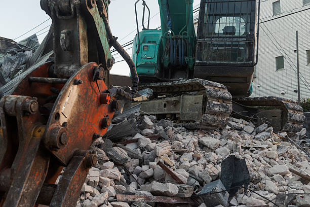 Excavator working over rubble and broken concrete.