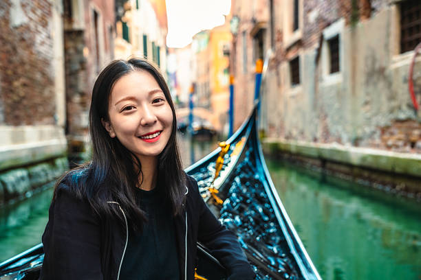 A beautiful Asian woman is taking a vacation on a gondola in Venice.