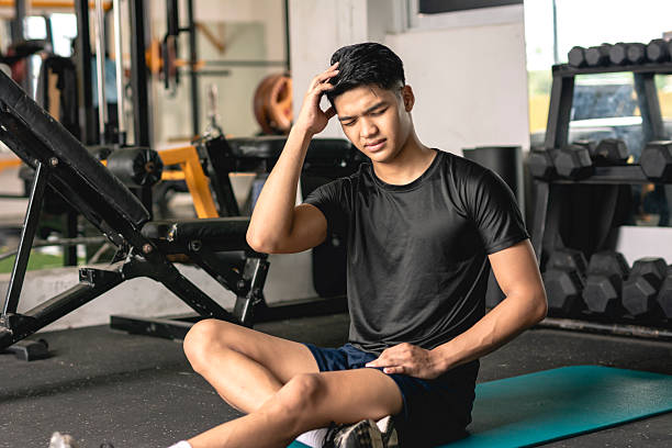 istock A young handsome asian man suffering from a headache. Looking frustrated and disappointed at himself while sitting on the mat at the gym. 2226906688