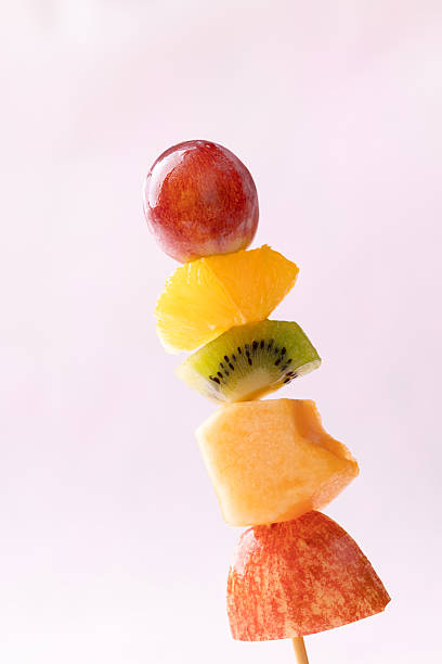 istock Fresh summer fruits skewer (grape, orange, kiwi, melon and apple) on pink background 2226907443