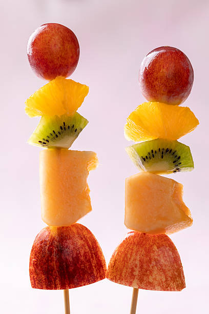 istock Fresh summer fruits skewer (grape, orange, kiwi, melon and apple) on pink background 2226907457