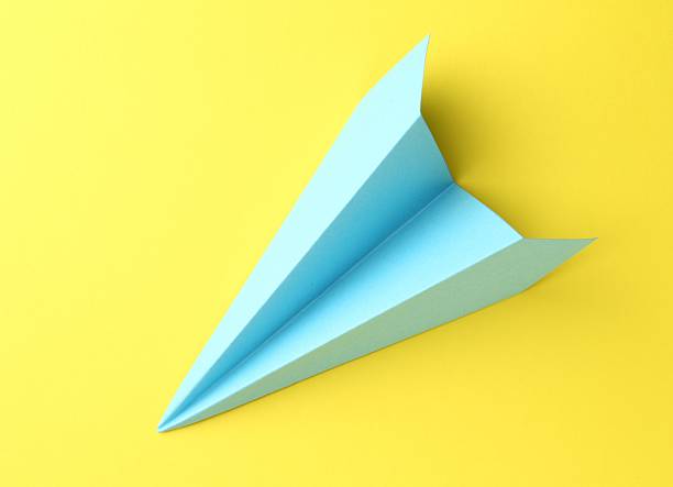 istock One handmade light blue paper plane on yellow background, top view 2226910610