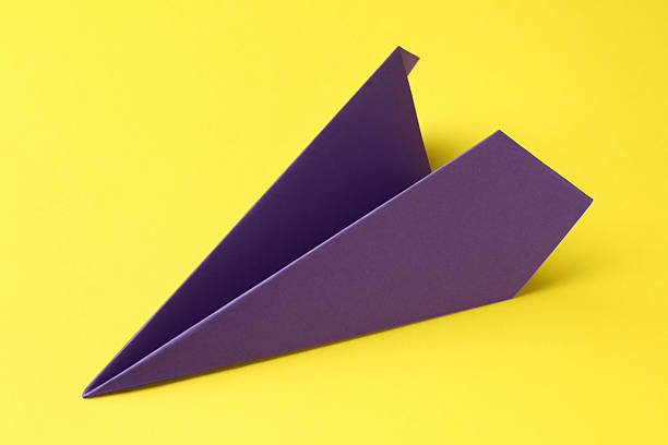 A paper airplane model made of wood holds a pink sticky note, ideal for reminders or messages.