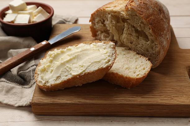 istock Fresh bread with butter on light wooden table, closeup 2226911274