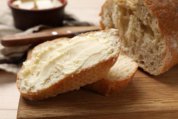 istock Fresh bread with butter on wooden board, closeup 2226911292
