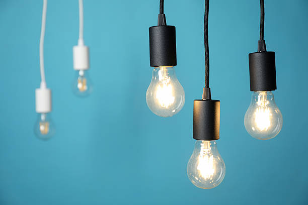 istock Light bulbs hanging on cords against blue background, selective focus 2226911784
