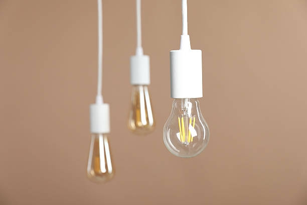 istock Light bulbs hanging on cords against beige background, selective focus. Space for text 2226911802