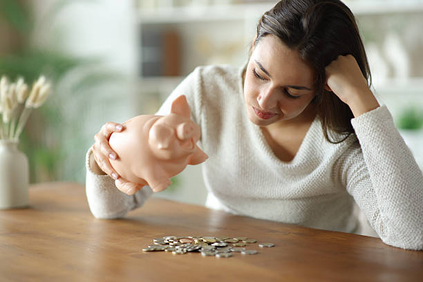 Frustrated woman checking money from piggy bank stock photo