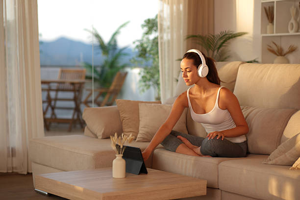 istock Yogi playing online yoga class on a couch at sunset at home 2226912496