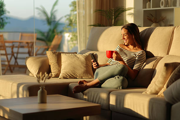 istock Happy woman using smart phone drinking coffee from red cup at home 2226912603