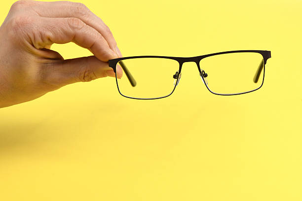 istock Hand holding plastic black glasses, isolated on yellow background. 2226916366