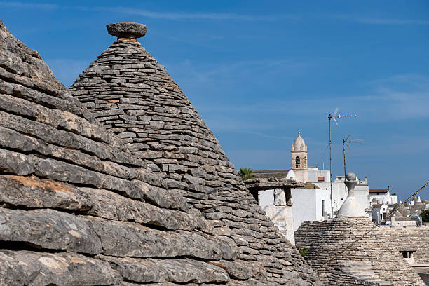 Close up of characteristic conical stone roofs of Trulli houses with the city of Albarobello, Puglia, Italy in the background