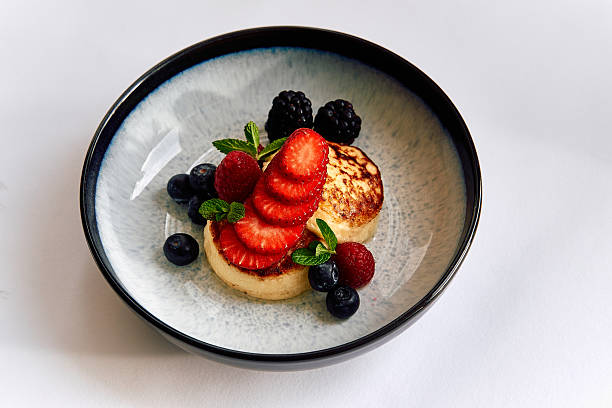 istock A Beautifully Presented Dessert Featuring Fluffy Pancakes Topped with Fresh Berries and Mint Leaves in a Stylish Bowl 2226920974