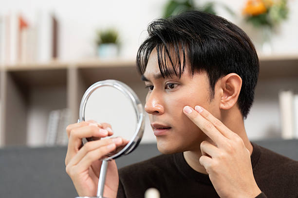 istock Skincare Routine. Young man examining skin with mirror for healthy complexion. 2226922493