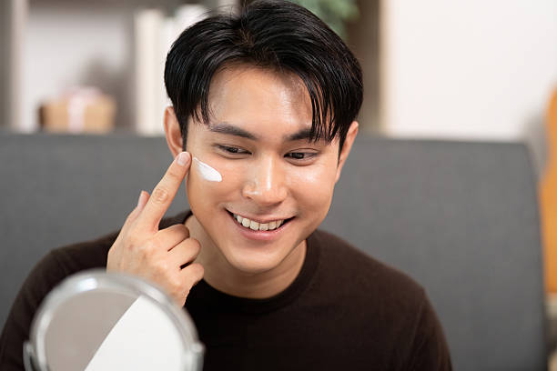 istock Skincare Routine. Young man applying moisturizer on face in front of mirror. 2226922675