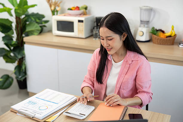 istock Work from Home Young woman managing tasks with calculator and documents 2226922747