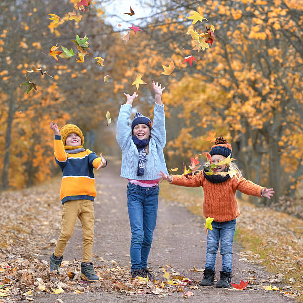 Crisp Fall Fun: Children Throwing Vibrant Leaves