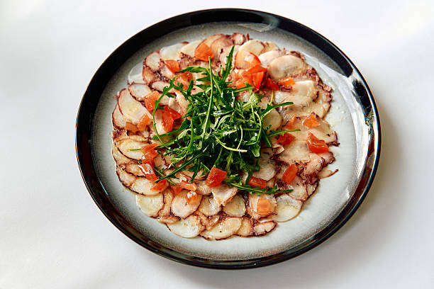 istock A Beautifully Arranged Plate Featuring Tender Raw Fish Carpaccio Topped with Fresh Arugula and Diced Tomatoes, Showcasing Culinary Elegance and Fresh Ingredients 2226926065