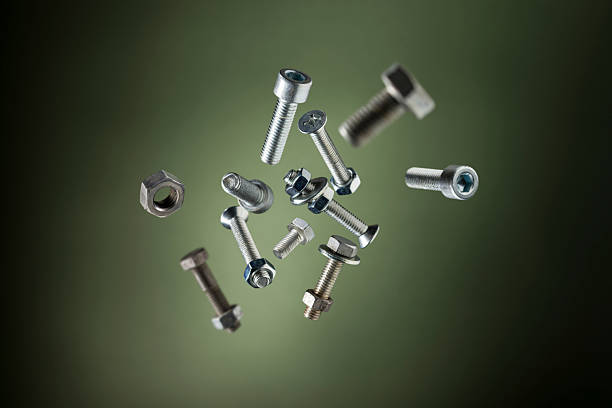 Variety of steel screws and bolts flying on green background.