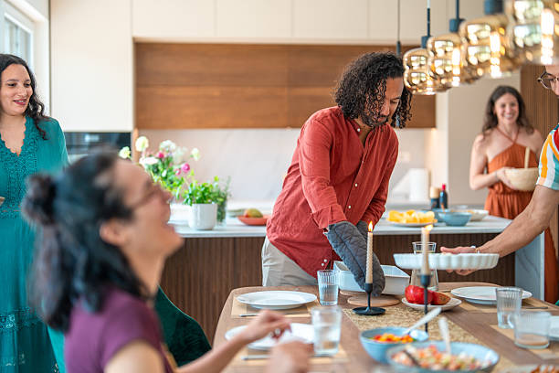 istock Hispanic Man Serving Hot Dish to Diverse Friends in Warm Home Setting 2226930002