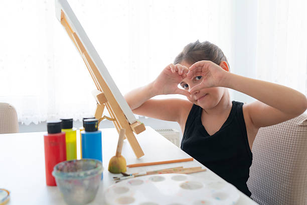 Cute girl painting at home.Cute girl drawing with a paint palette and a paintbrush