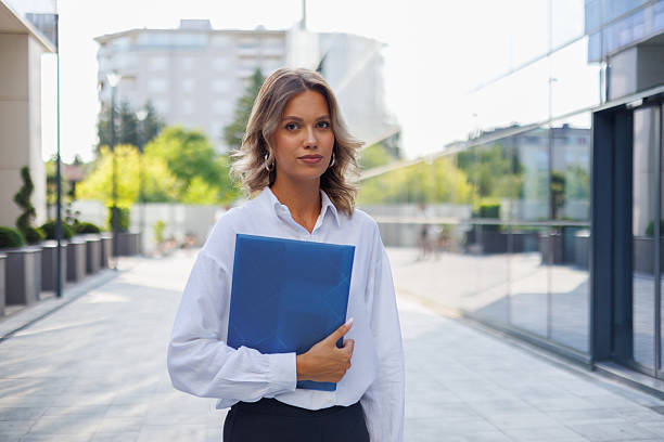 istock Young businesswoman walking confidently outdoors, holding a folder while navigating the bustling city streets, exuding professionalism and style 2226931445