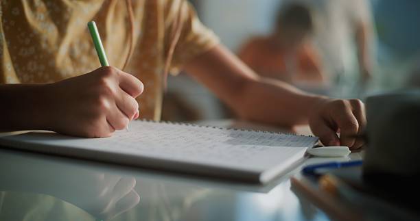 istock Close Up Shot of Elementary School Girl Writing Exam or Doing Task in Notebook 2226931450