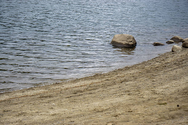 istock A rock is sitting in the water next to a sandy beach 2226938766